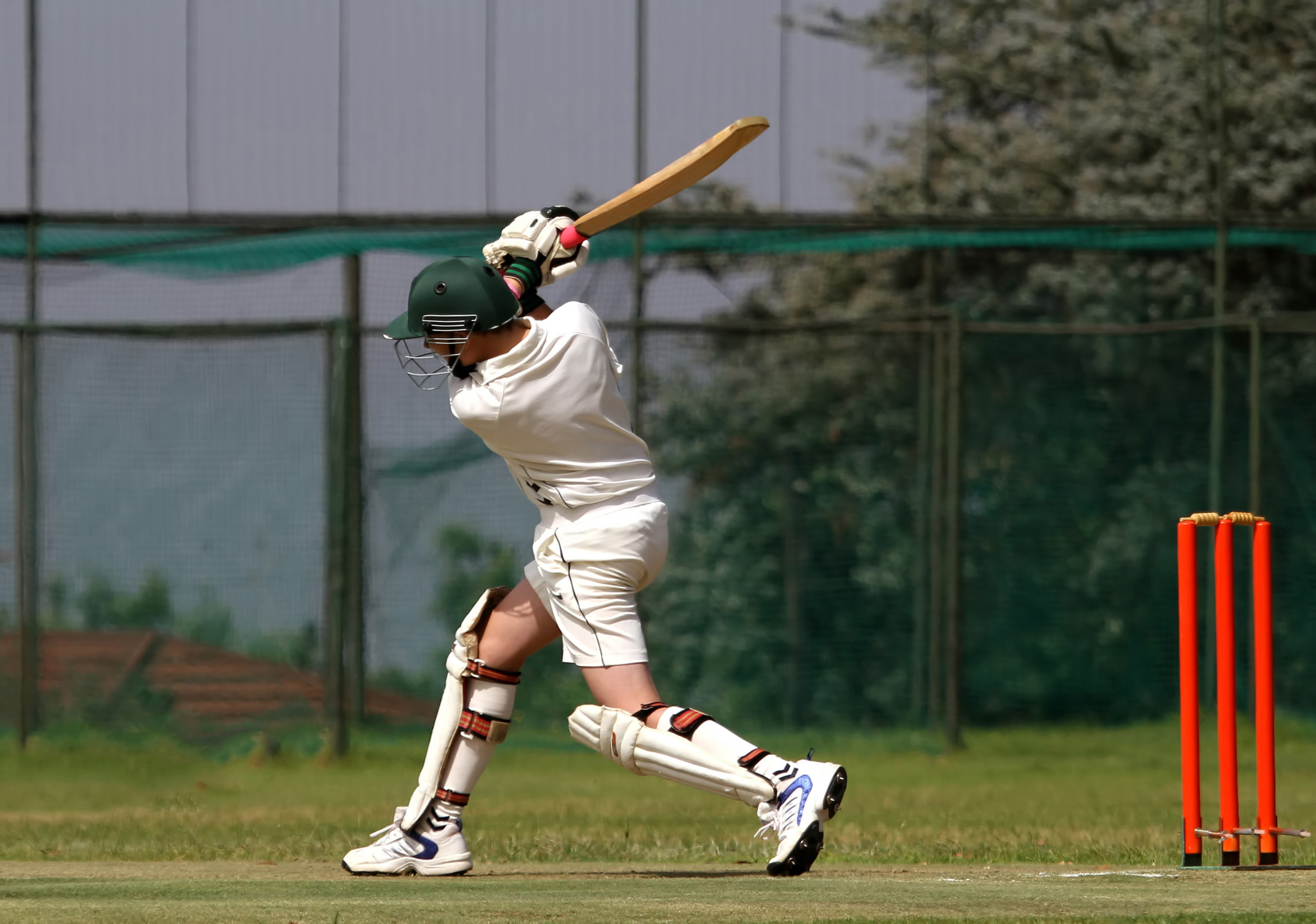 A young left hand cricket player drives the ball through the covers and ends with a beautiful follow-through